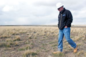 Jonah Energy’s Paul Ulrich inspects a former drill pad that was replanted with native vegetation about five years ago. The region’s arid climate makes it difficult to recover plant life after a disturbance. (photo by Phil Taylor)