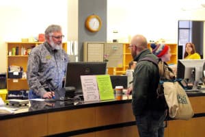 Harry Whitlock, University of Wyoming library specialist, assists a student at the Coe Library reference desk. The hiring freeze for all state employees is expected to save $16 million to $18 million dollars, or 10 percent of the $159 million deficit for 2016. (Gregory Nickerson/WyoFile)
