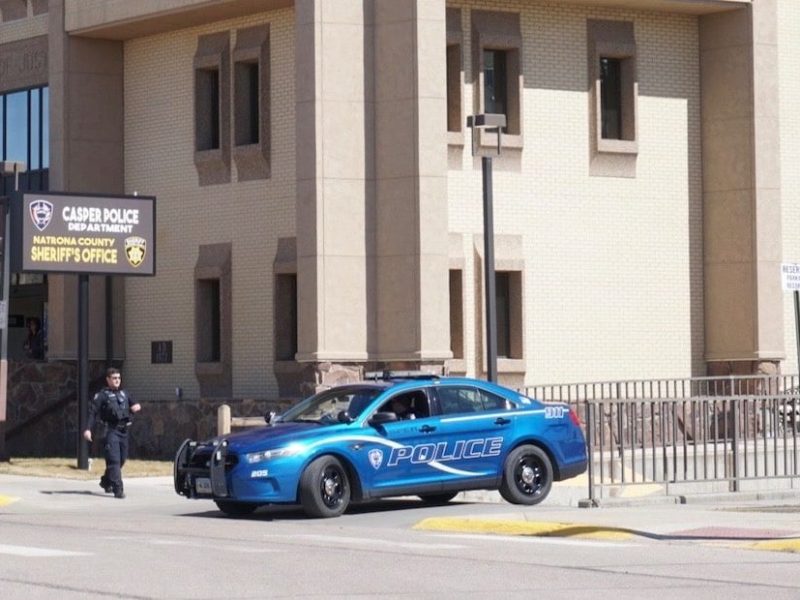 A police car drives in front of the Casper Police Department headquarters