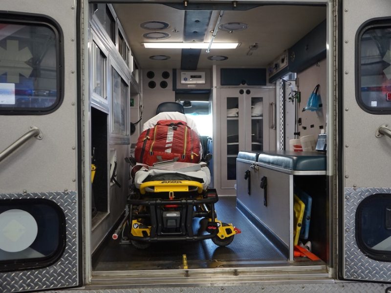 A gurney with medical supplies rests in the back of an ambulance