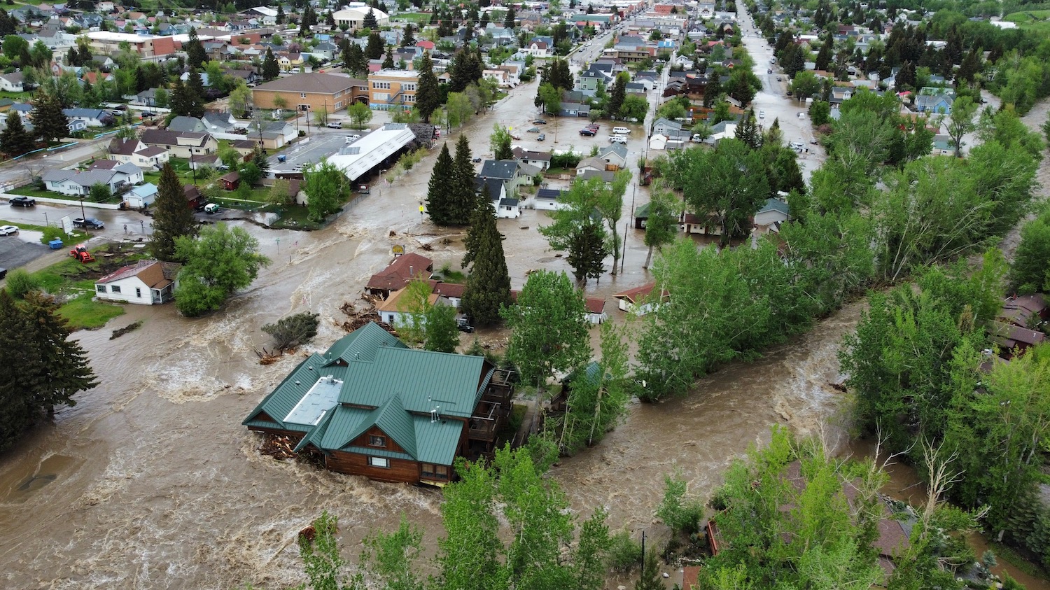 Brown water swirls down streets and around houses, infiltrating some