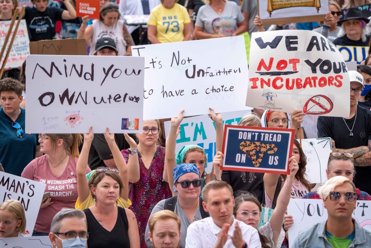 A group holds signs denouncing the fall of Roe