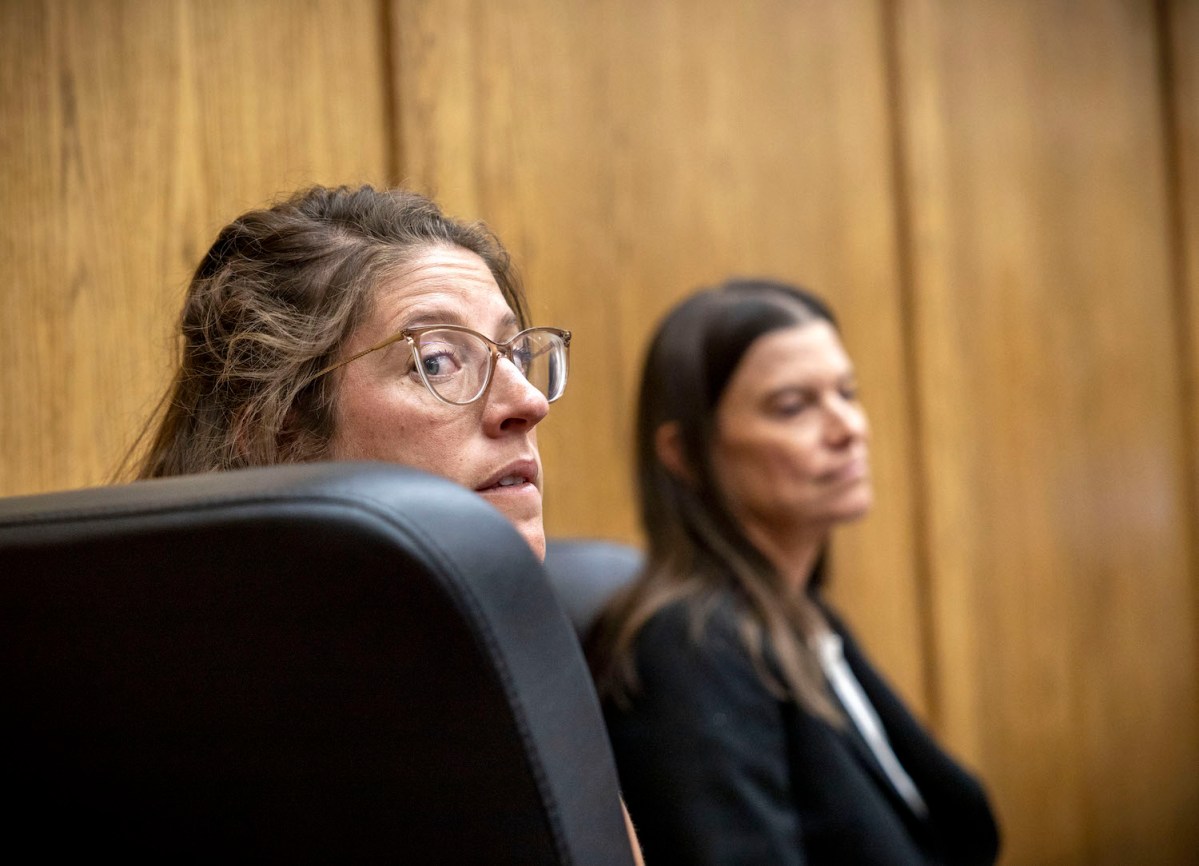 Danielle Johnson peaks behind her over a large black chair