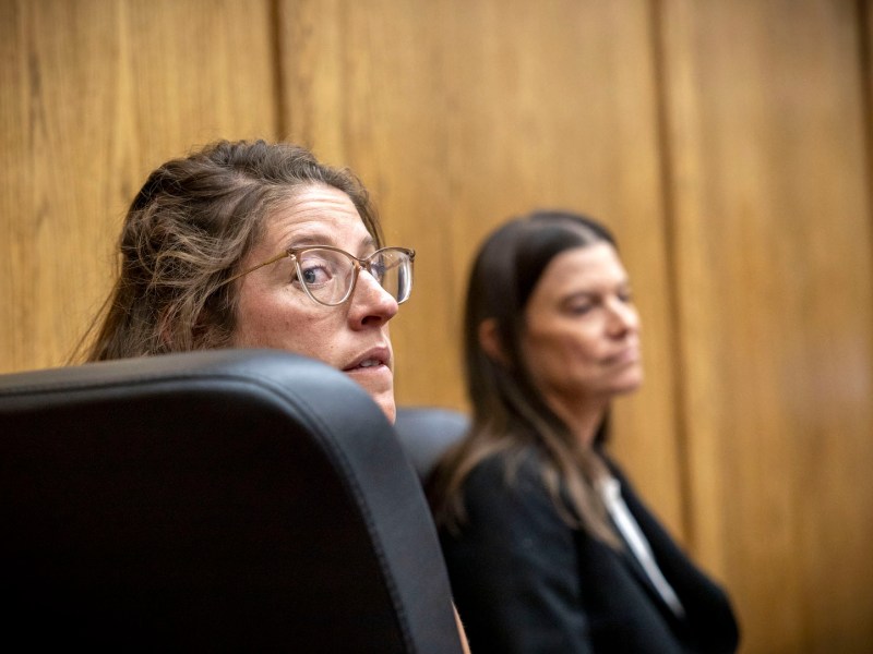 Danielle Johnson peaks behind her over a large black chair