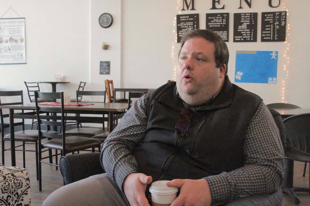 Barbuto sits with a cup of coffee in a coffee shop