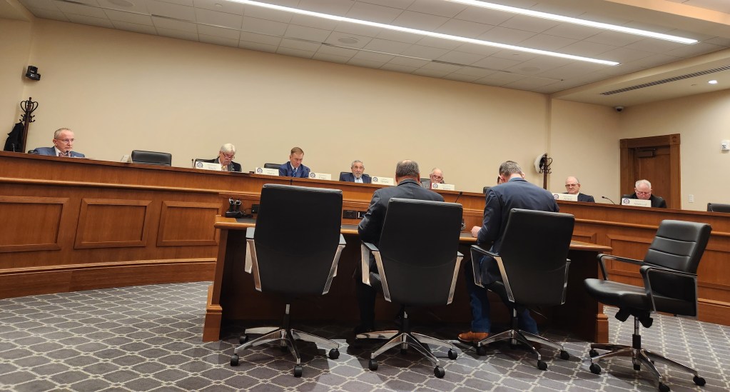 The backs of Salazar and Lindholm and the faces of an white men sitting on the agriculture committee Feb 14