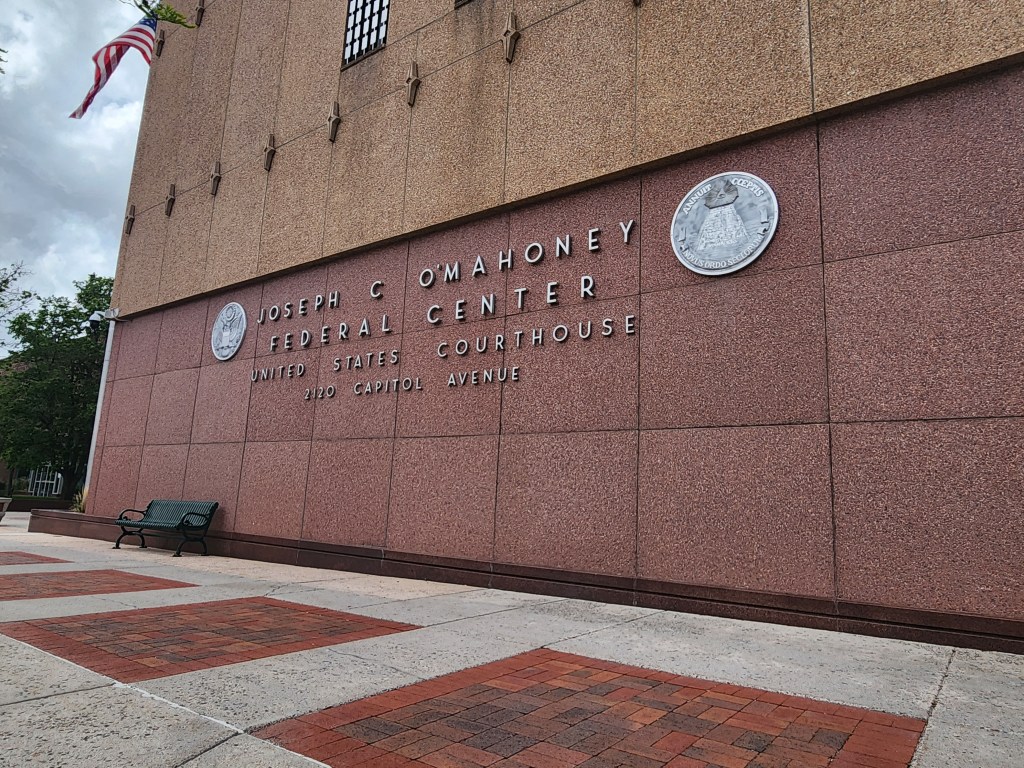 A picture of the U.S. District Court in Cheyenne. The sign out front says "Joseph C O'Mahoney Federal Center United States Courthouse 2120 Capitol Avenue"