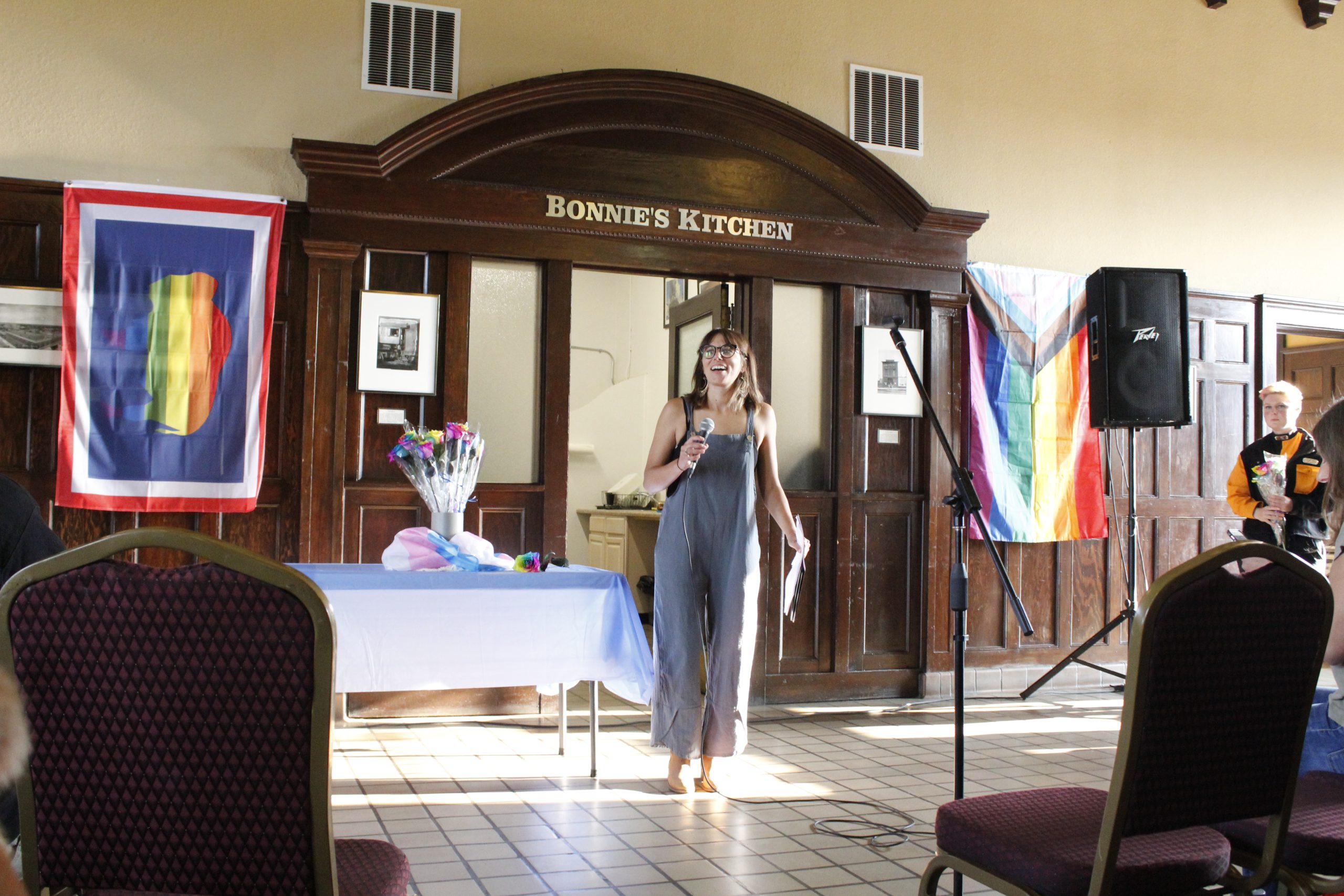 Rose Curtis stands in the train depot in Laramie with pride flags hanging on either side of her