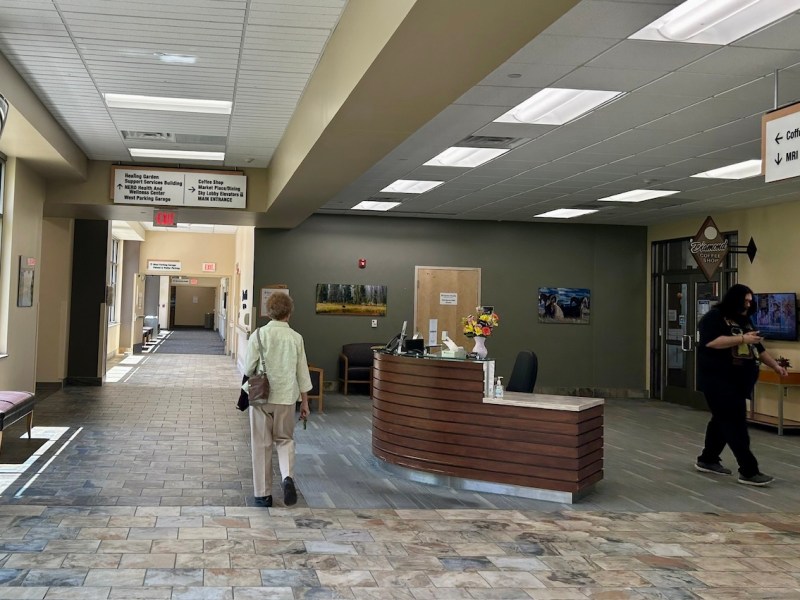 A gray and tan lobby that's mostly empty with a receptionist desk