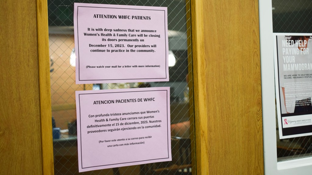 Signs hang on a door window telling WHFC patients that the office will close Dec. 15. One is in English, the other Spanish