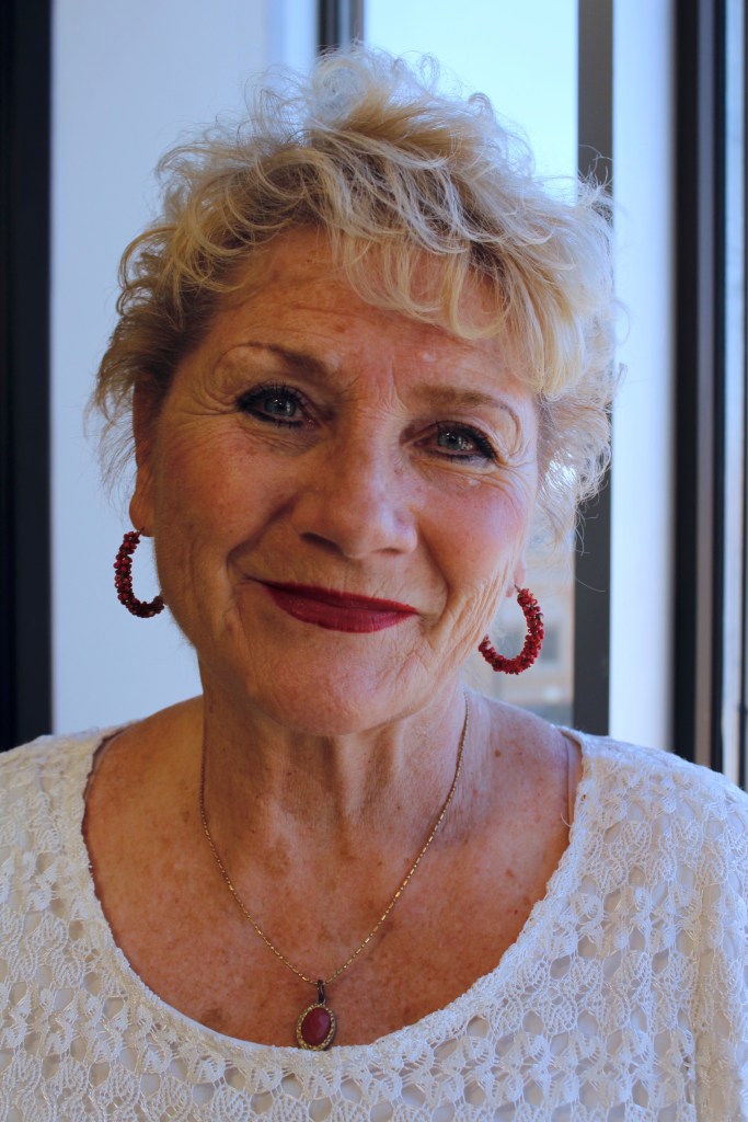 Susan's grins with her red lipstick, red hoop earrings and red necklace