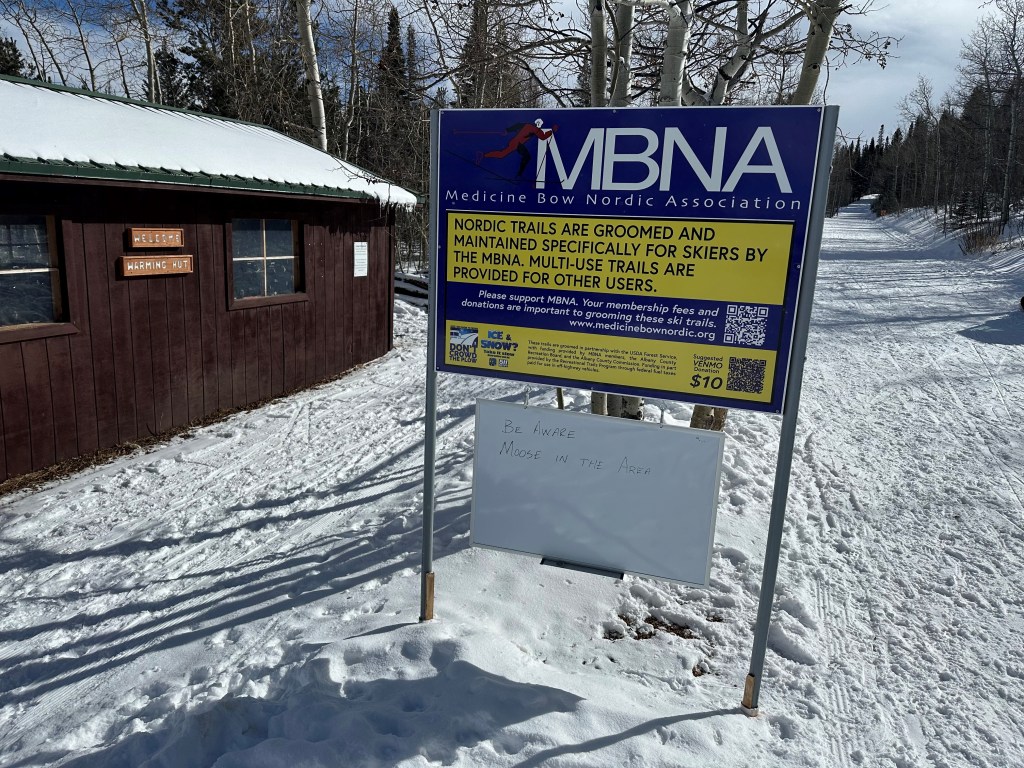 A Medicine Bow Nordic Association sign with a white board below saying "Be Aware, Moose in the Area"