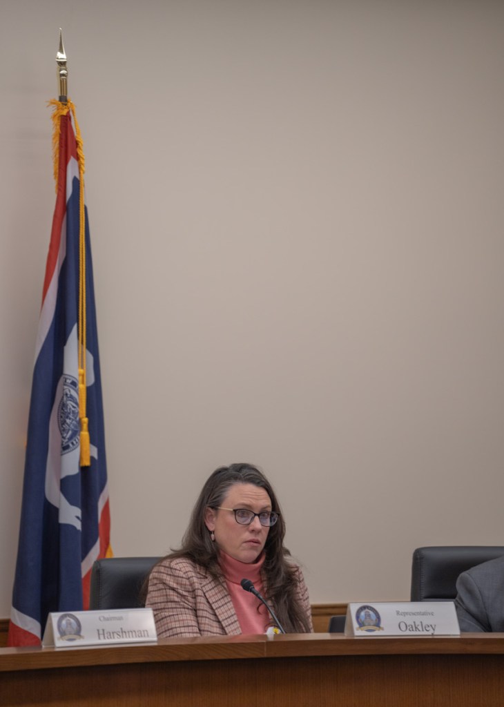 Ember Oakley sits behind a long committee desk at the legislature
