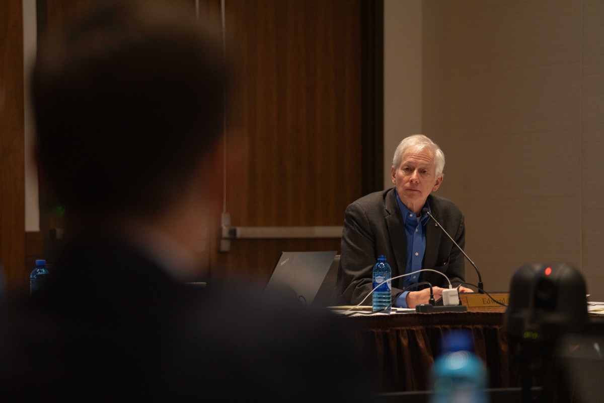 Seidel sits at a table beside UW trustees