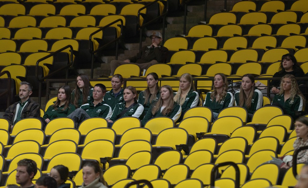 A team in matching green sweaters sits in the stands