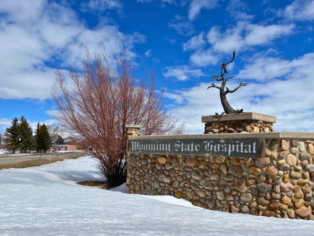 A sign that says "Wyoming State Hospital" on a rock-covered structure