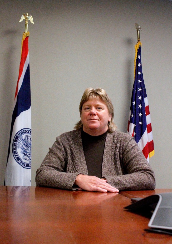 Judge Johnson sits at a wooden table, flanked by American and Wyoming flags