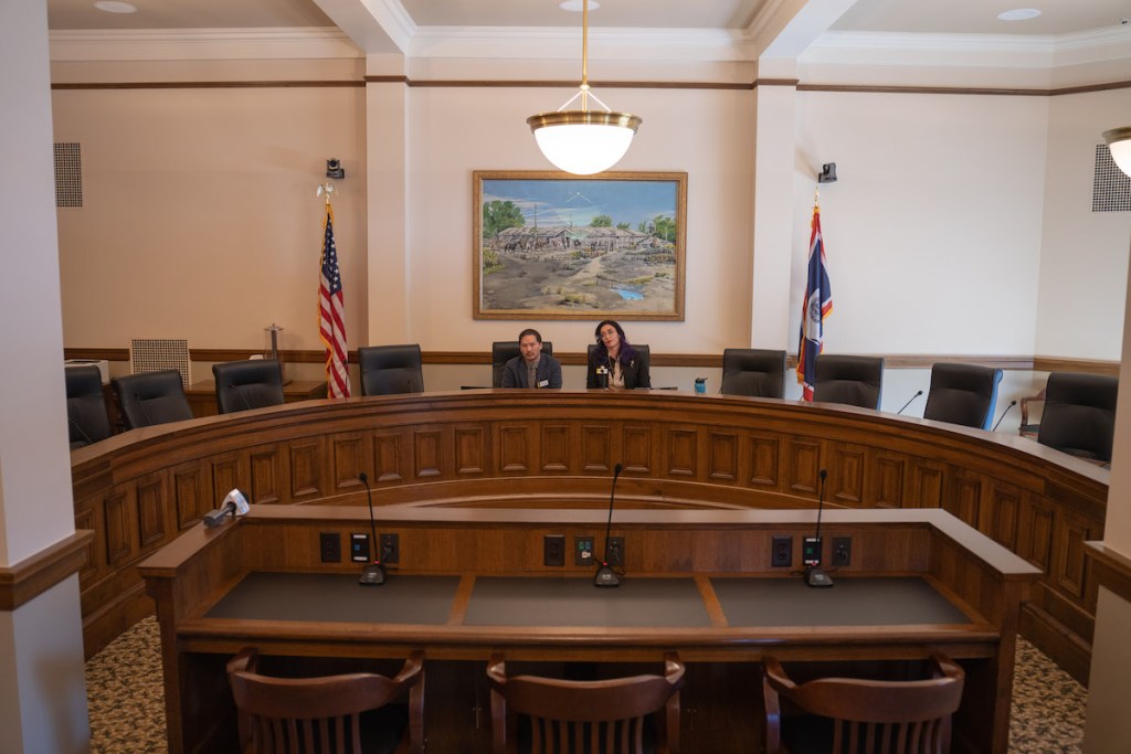 Two people sitting at a long wooden table