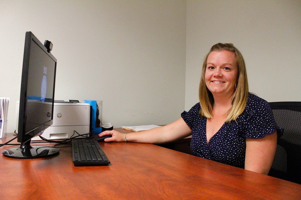 A woman sits at a desk with a computer