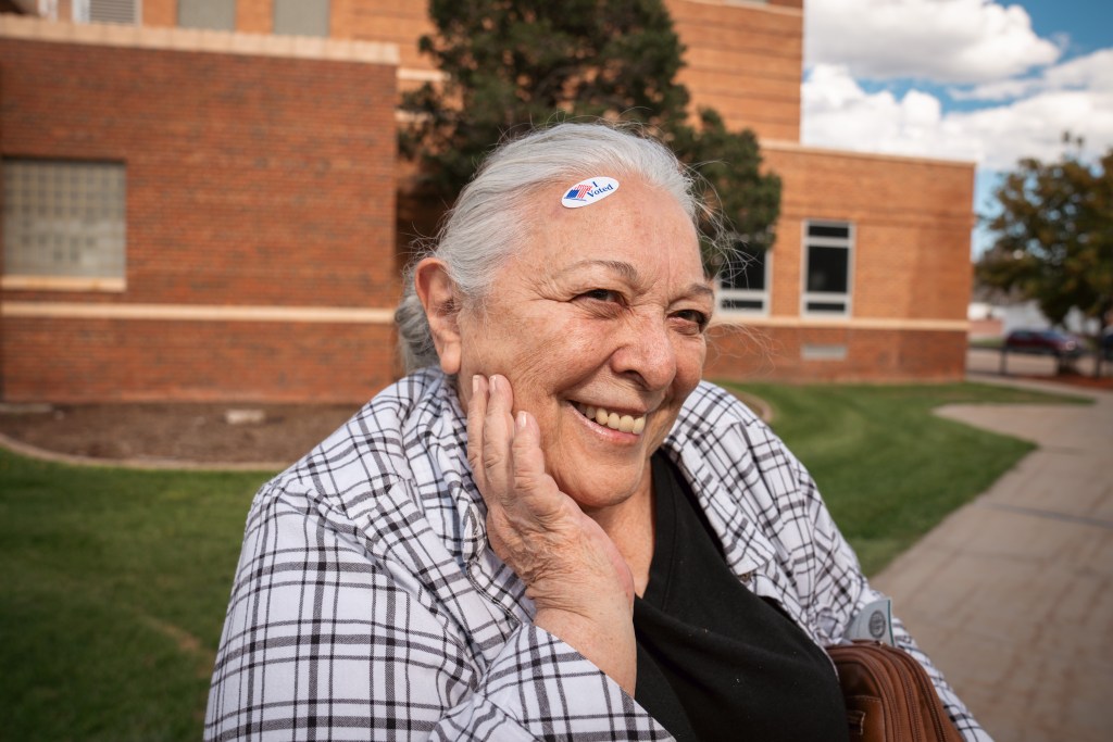 A woman smiles with an "I voted" sticker on her forehead