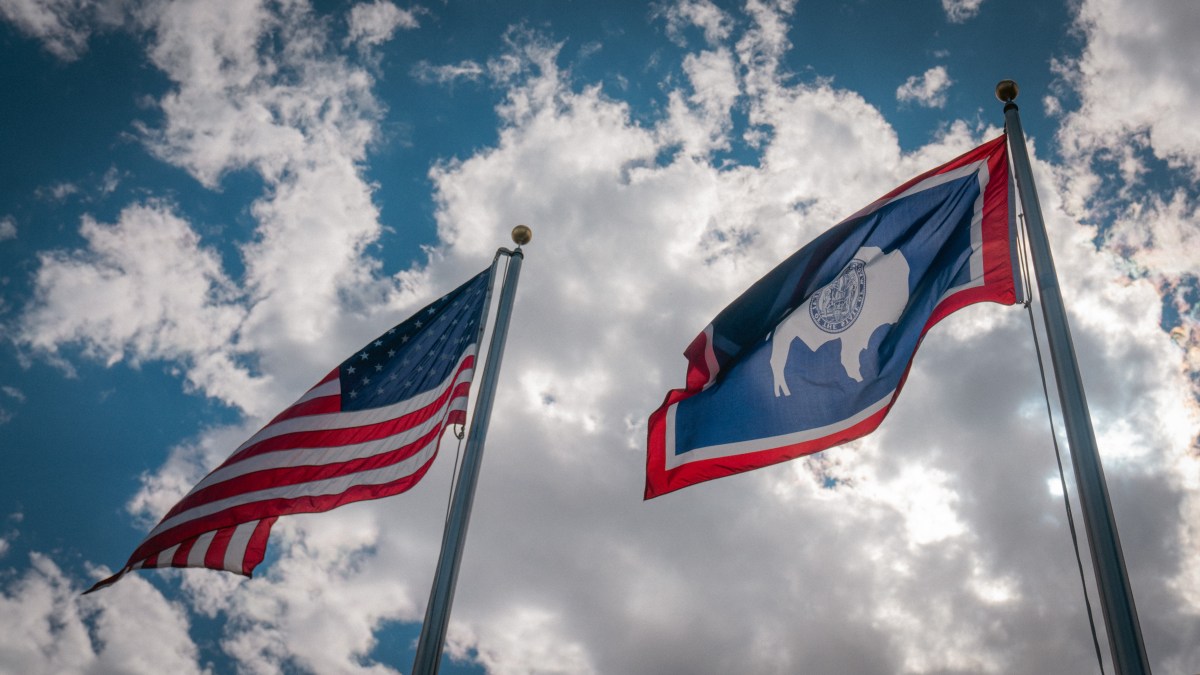 An American flag flying slightly higher than a Wyoming flag