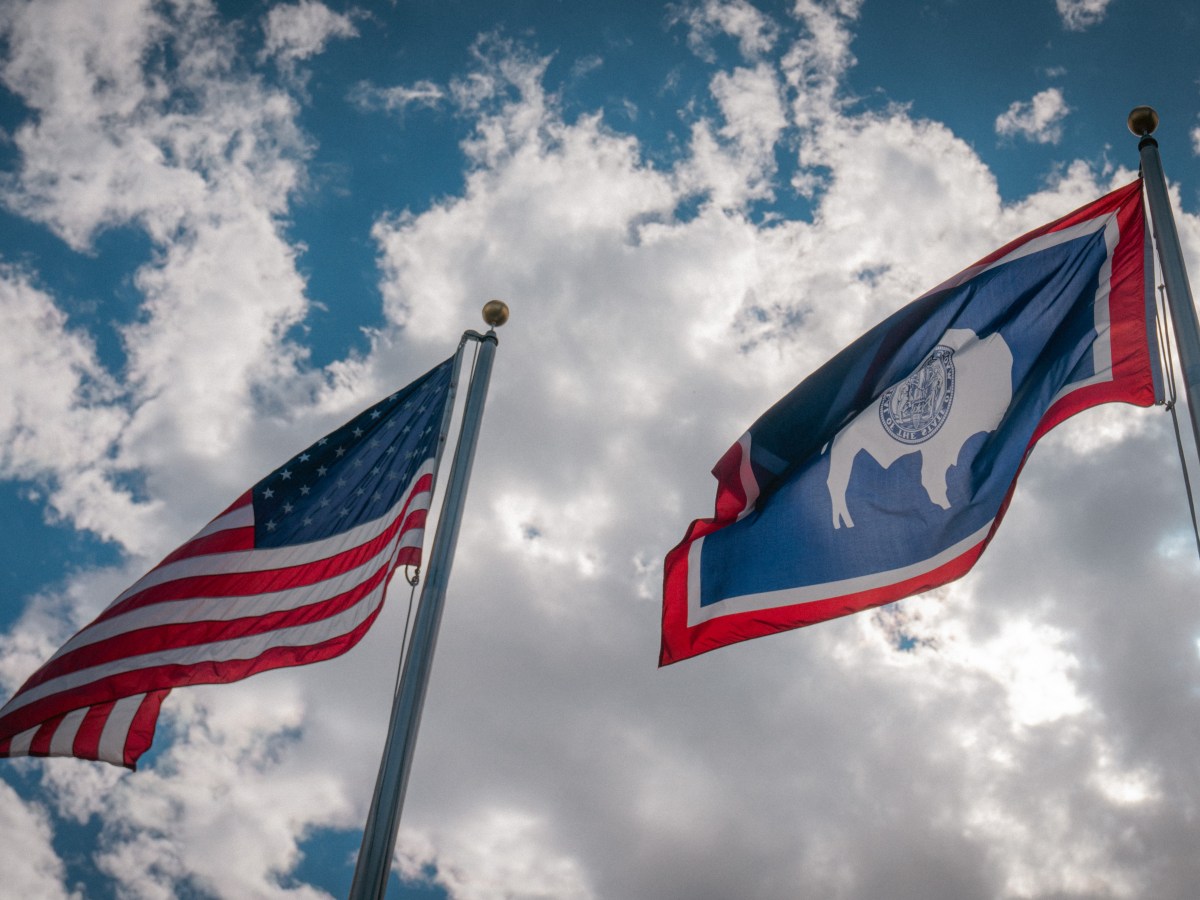 An American flag flying slightly higher than a Wyoming flag