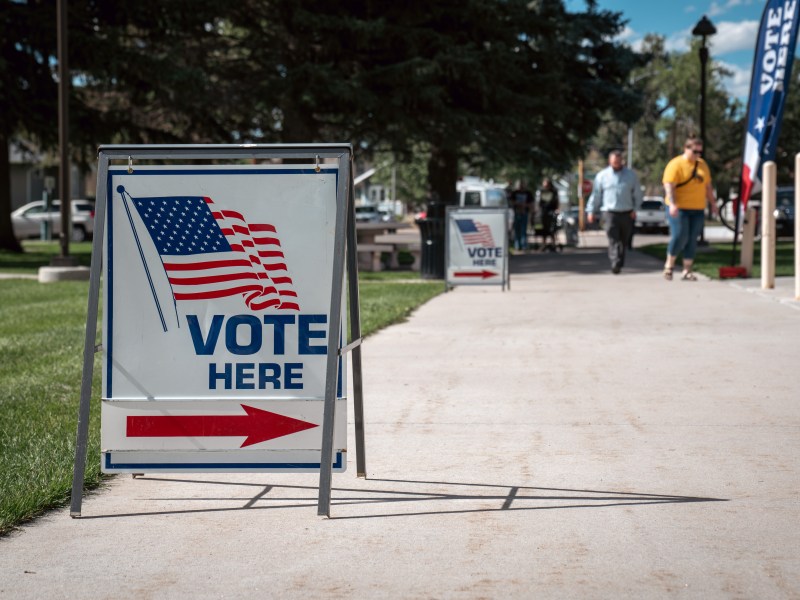 A sign with an American flag and arrow that says "vote here."