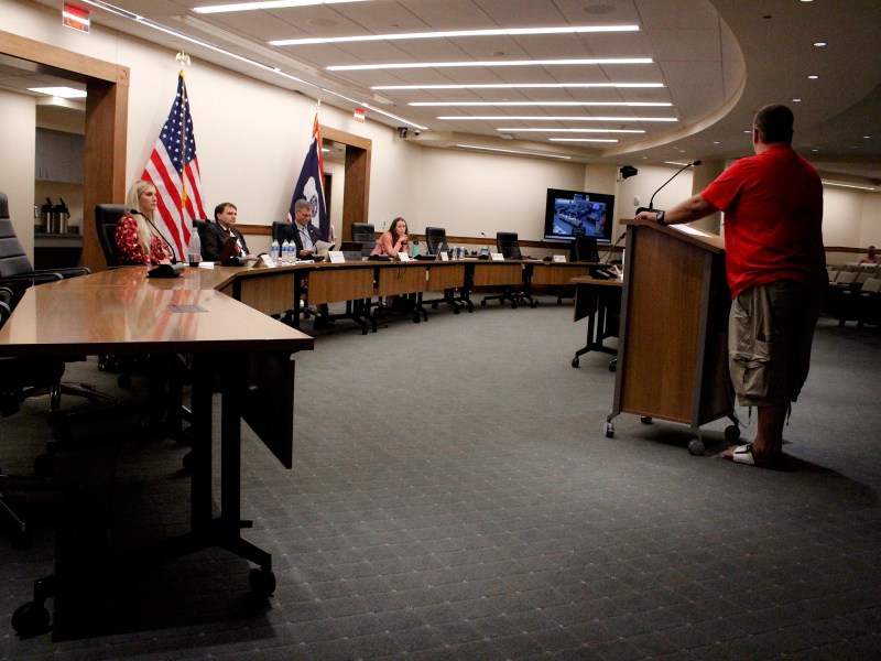 A man stands at a podium in front of a table with state leaders