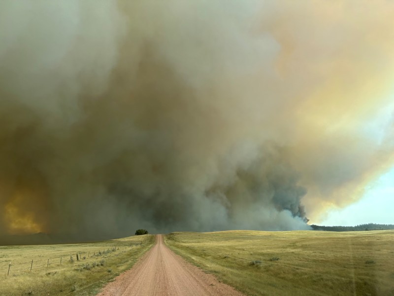 A dirt road leading to a massive plume of smoke